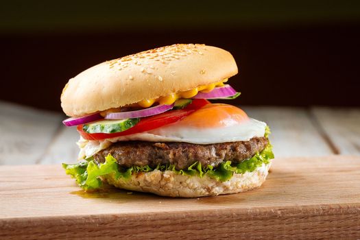 Classic burger with egg on the wooden board