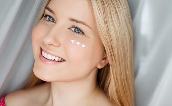 Beautiful woman with skincare cream on her face