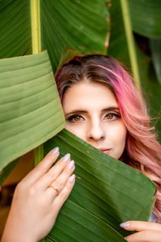 Woman portrait pink hair banana leaf. A beautiful young woman among the huge green leaves of a banana tree.