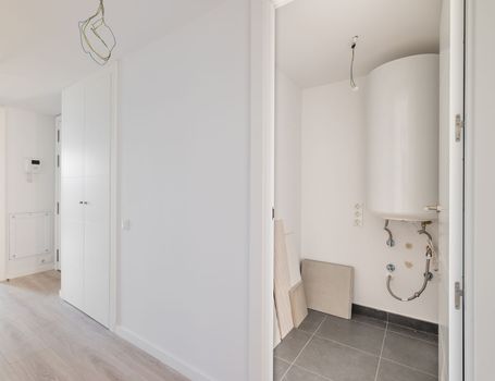 White corridor with an entrance to the boiler room with a water heater and build-in wardrobe during renovation. Concept of building house with modern communications