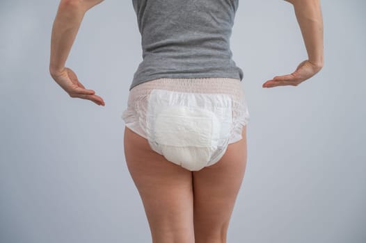 Rear view of a woman pointing at adult diapers. Incontinence problem.