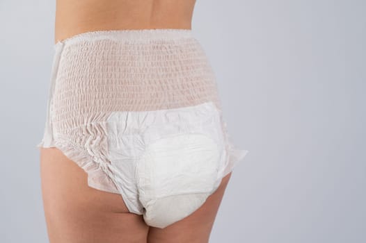 Rear view of a Woman in adult diapers on a white background. Incontinence problem.
