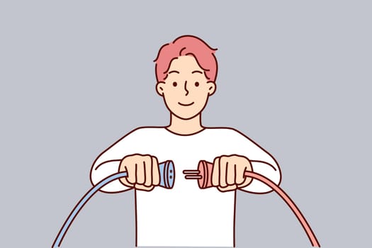 Man holding two cords with high voltage wish to connect wires to start electrical equipment
