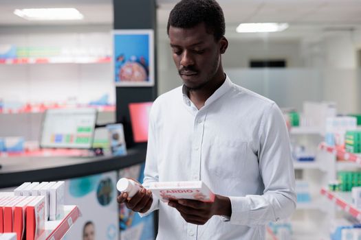 Young african american man choosing cardiovascular supplements in drugstore