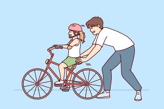 Loving father helps pre-teenage daughter learn to ride bike. Happy childhood for little girl in helmet learning to ride bicycle under supervision of caring dad or brother