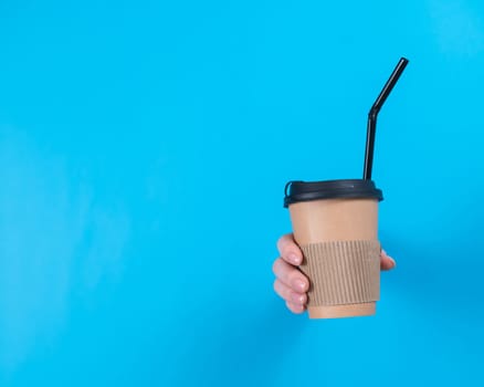 A woman is holding a cardboard cup of coffee. A woman's hand sticks out of a hole in a blue background.