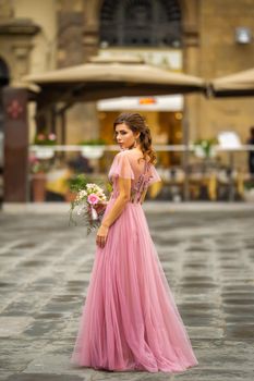 A bride in a pink dress with a bouquet stands in the center of the Old City of Florence in Italy
