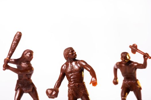 Large toy figures of primitive people on a white background