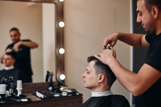 hairdresser does haircut for man in barber shop