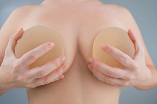 Caucasian naked woman trying on silicone breast implants.