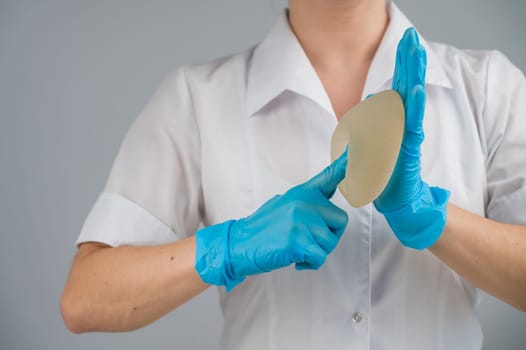 A plastic surgeon shows a breast silicone implant.