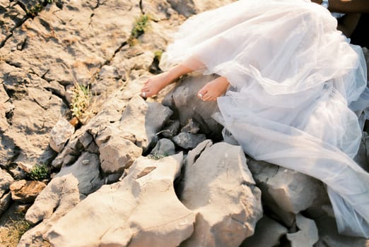 Bare feet of the bride in a white puffy dress on the stones