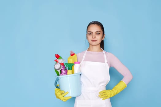 woman in gloves holding bucket with cleaning supplies