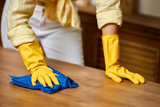 woman in gloves holding bucket with cleaning supplies