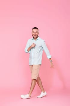 handsome man walks isolated on pink background