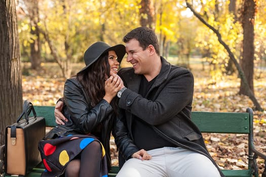 In love happy young couple sitting on a bench in autumn park