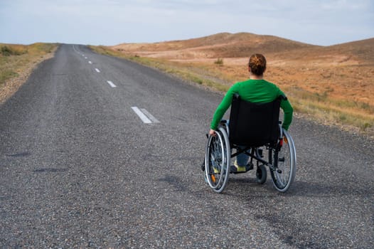 Woman in a wheelchair on a highway in the steppes.
