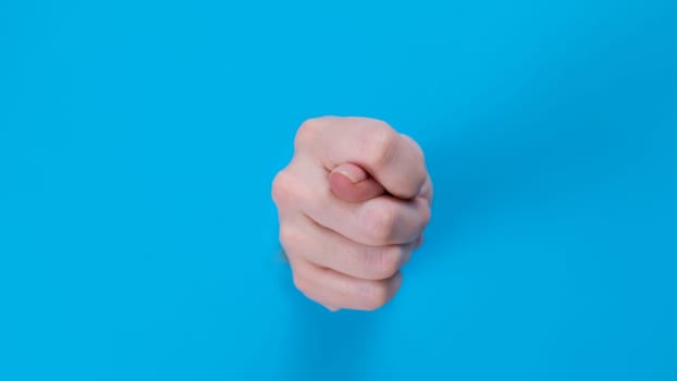 Female hands sticking out through a hole on a blue background.