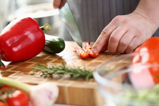 Chef cuts chili peppers on board closeup