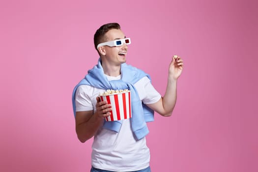 Young caucasian man in 3d glasses eating popcorn