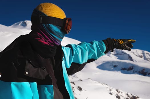 Sportsman pointing with his hand while skiing on a snowy slope. A traveler, a tourist, pointing his hand somewhere in the direction of the mountains. Winter sports activity