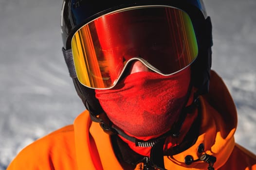 Portrait of a snowboarder. Ski goggles and ski helmet on a man looking at the camera, close-up. Holidays in the ski resort