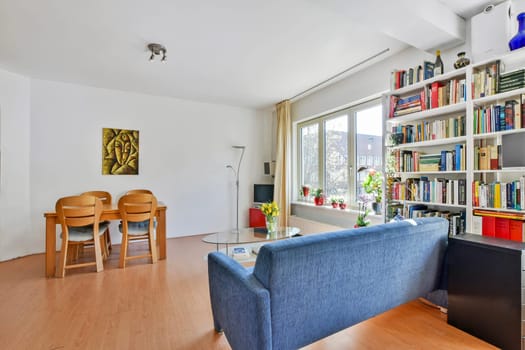 Amsterdam, Netherlands - 10 April, 2021: a living room with books on the shelves and a blue couch in the center of the room is a coffee table