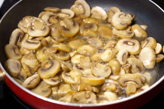 Mushrooms being fried in a frying pan, the process of cooking food. Concept.