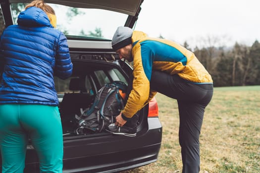 Hikers getting ready at the trunk of their car on the parking place
