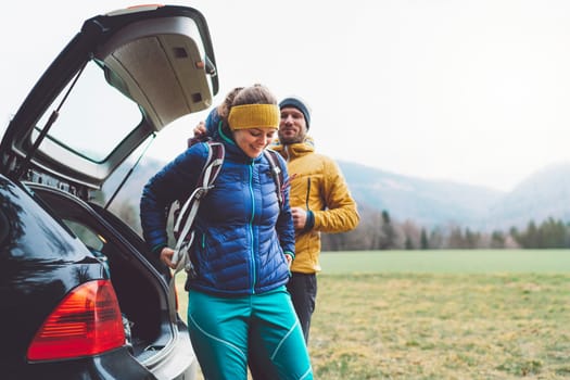 Couple of hikers getting ready for a hike taking things out of the trunk of their car
