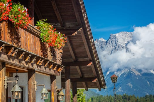 Alpine Chalet with flowers at springtime and Zugspitze mountain, Bavarian Alps