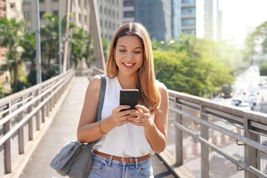 Brazilian Caucasian entrepreneur walking in Sao Paulo downtown messaging with a cellphone