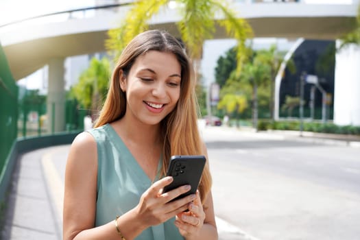 Close-up of happy woman in city using OVP or social media platform on smartphone
