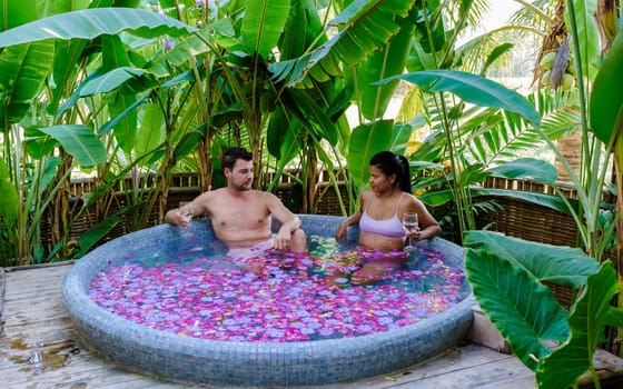 Men and women at a bathtub in the rainforest of Thailand during vacation with flowers in the bath