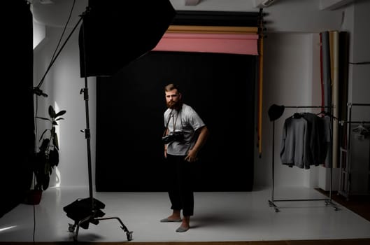 Professional handsome bearded male photographer with bunch of vintage photo cameras in photo studio.