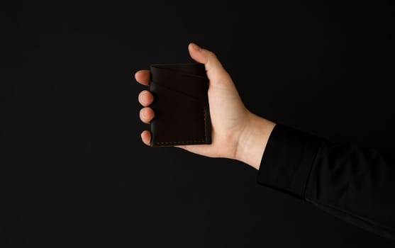 Brown empty men's business handmade leather card holder in a man's hand.