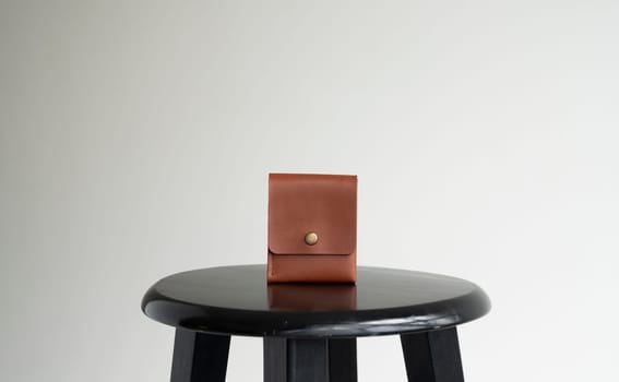 Orange men's business leather card holder on a black chair with a white background. Men's accessories.