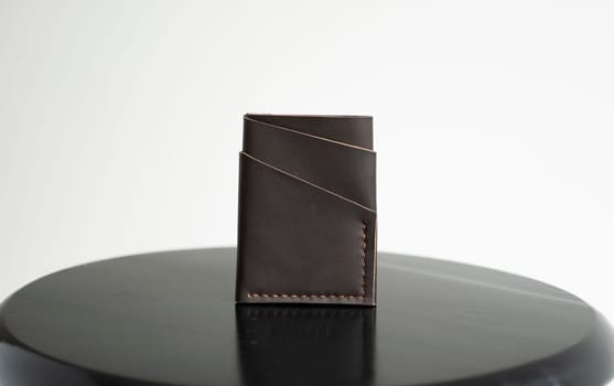 Brown men's business leather card holder on a black chair with a white background. Men's accessories.