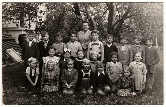 Vintage photo shows classmates (about 10 years old) with teacher