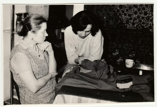Vintage photo shows women preparing to sew a dress.