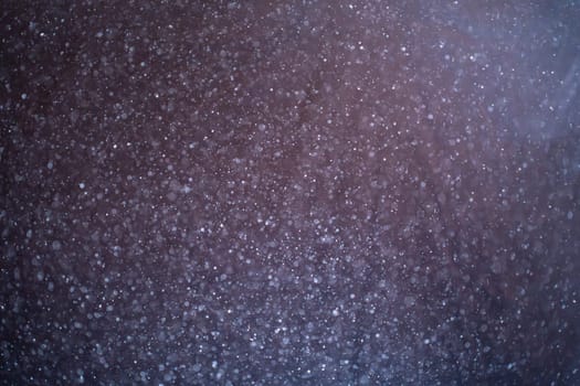 Dust particles floating on black background. Glittering sparkling flickering glowing.