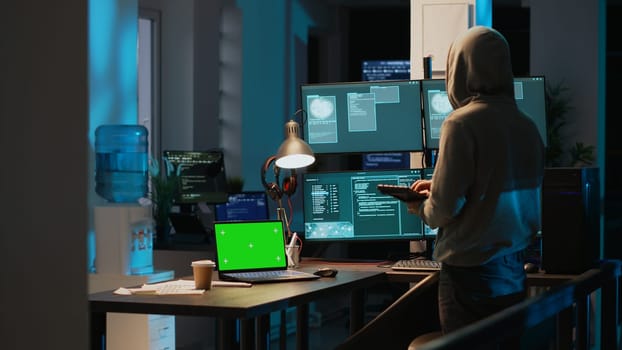 Male hacker using greenscreen to break into IT server