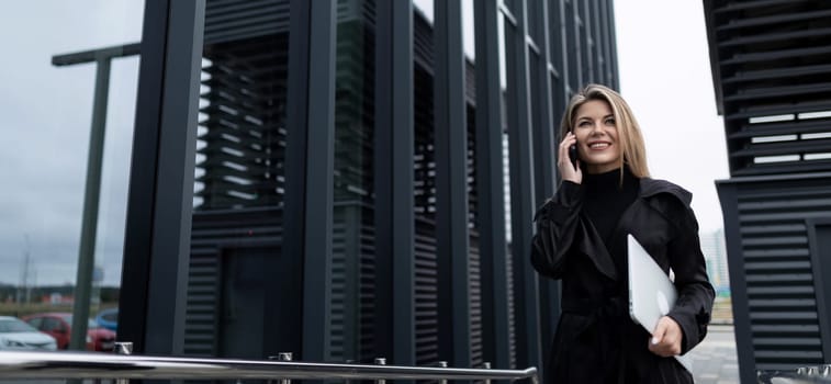wide horizontal photo of a confident business woman in front of an office building