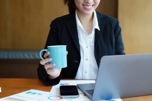 Portrait of a young woman drinking coffee while using a computer