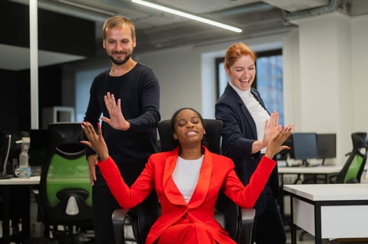 Caucasian red-haired woman, bearded caucasian man high five african american young woman in the office.