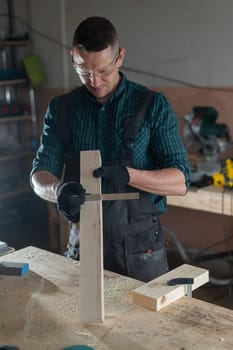 Carpenter measures a wooden board while working in a workshop.