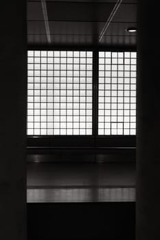 Vertical grayscale shot of illuminated glass tiles in a subway station in Cologne, Germany
