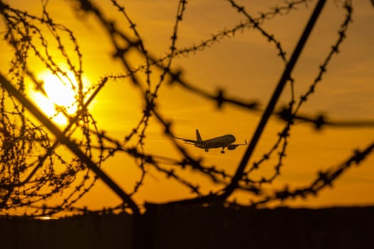 View through barbed wire on a flying plane at sunset