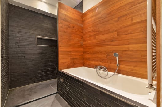 a bathroom with a bath tub and a wooden wall