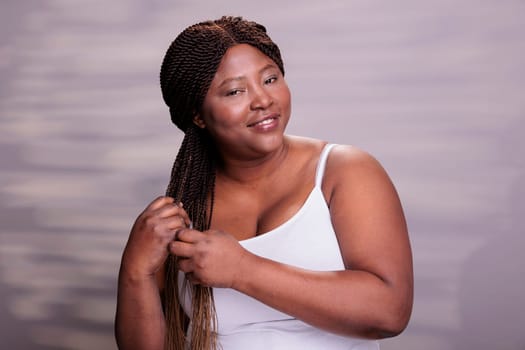 Curvy happy lady making african braids hairstyle portrait